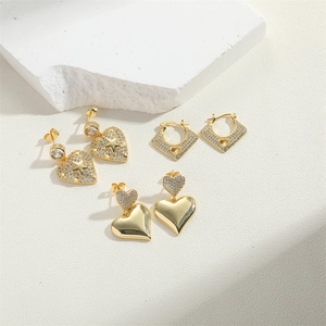 Close-up of luxury gold heart and star earrings with cubic zirconia on white stone