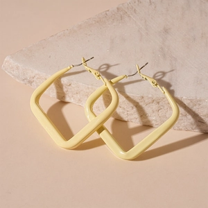 Detail showing a light yellow geometric square drop earring on a natural stone base