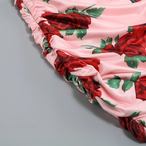 Détail du tissu satiné rose avec imprimé roses et texture froncée de la robe