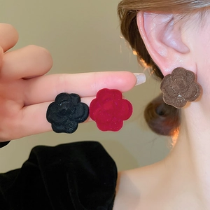 Detail of camellia-shaped velvet earrings in black, burgundy, and coffee colors