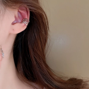 Macro shot of a silver layered ear cuff with crisscross zircon design on a model's ear