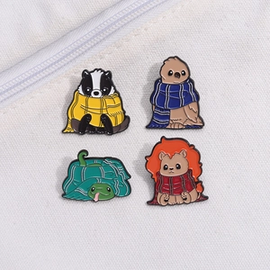 Lot de quatre épingles animaux en émail avec écharpes colorées sur fond de tissu blanc