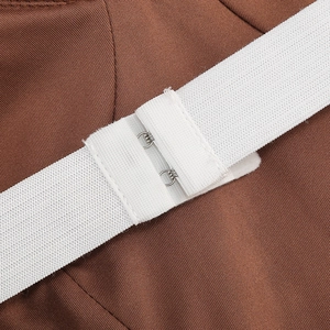 Dettaglio macro di fettuccia elastica bianca e gancio in metallo su vestito marrone