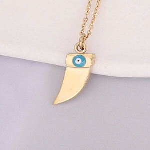 Macro view of gold crescent moon pendant featuring a blue enamel evil eye design
