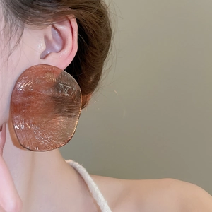 Macro detail of amber resin earrings with unique ice crack texture on a fashion model