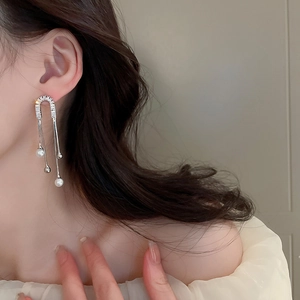 Detail of luxury emerald leaf tassel earrings with silver needle and white pearl drops