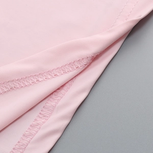 Dettaglio delle cuciture dei ricami rosa di qualità e del tessuto liscio sull'abito