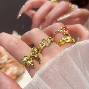 Detail of 18k gold plated rings with bow design and red gemstone on a model's hand