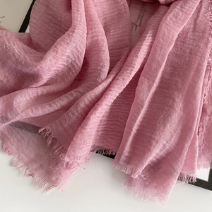 Detail of pink cotton linen scarf featuring natural wrinkled texture and fringe edge