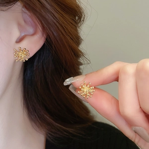 Macro shot of gold firework stud earrings featuring a radiant metallic burst design