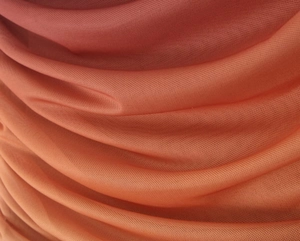 Dettaglio ravvicinato del tessuto mesh sfumato da arancione a rosso-arancio con pieghe