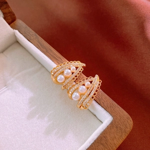 Detailed close-up of gold plated pearl earrings with zircons on a wooden jewelry box