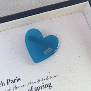 Détail d'une pince à cheveux cœur bleue en acétate avec gravure dorée à la main