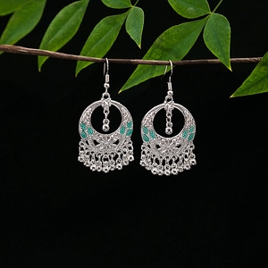 Detail of silver ethnic drop earrings with green beads and beads tassels on black background