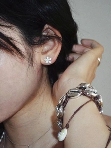 Close-up of S925 sterling silver flower earrings with blue stone on female model
