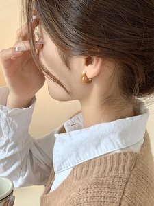 Close-up of minimalist brown resin C-shaped hoop earring worn by a female model