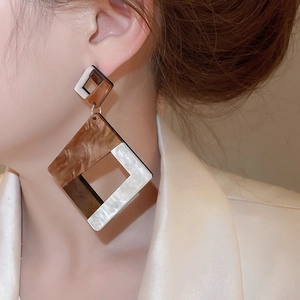 Macro detail of geometric brown marble acrylic drop earrings worn by a model