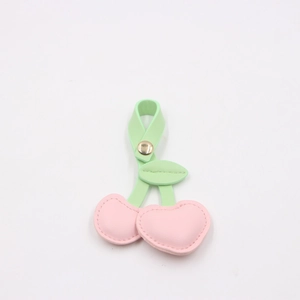 Close-up of pink leather cherry charm with green stem and high-quality gold clasp