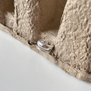 Detailed view of silver minimalist ear cuff with irregular texture on brown texture