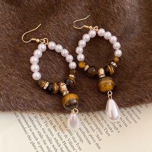 Detail of vintage tiger eye and pearl hook earrings with golden metal spacers
