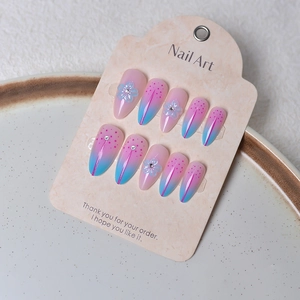 Detail of pink and blue gradient press-on nails with 3D blue flowers and rhinestones