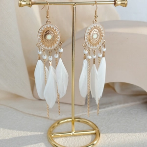 Detail of bohemian long feather earrings with gold alloy and white seed beads