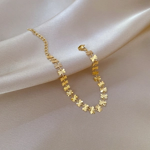 Close-up of golden geometric butterfly chain with adjustable clasp on champagne silk
