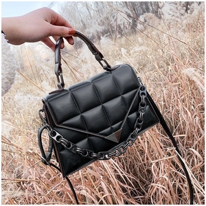 Detail of black quilted PU leather handbag with chain strap and triangle metal buckle