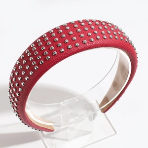 Detail of red leather headband with silver round studs and beige inner lining texture