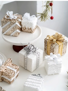 Detail of glittery champagne and white Christmas gift box ornaments on a white tray