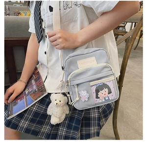 Sac bandoulière en toile bleu clair avec pendentif ours blanc porté par un mannequin