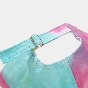Detailed close-up of adjustable silver buckle and tie-dye canvas texture on baseball cap