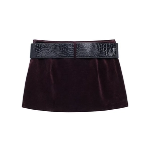 Détail d'une jupe en velours bordeaux avec ceinture en similicuir gaufré crocodile