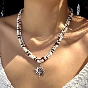 Close-up of double-layered beaded necklace with coconut shells and silver sun pendant