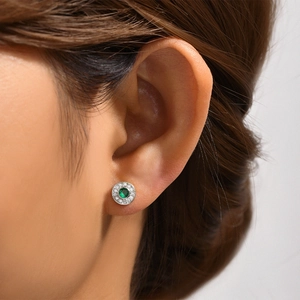 Close-up of S925 silver stud earrings featuring round emerald stones and diamond accents