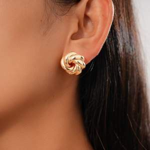 Close-up of a gold knot earring worn by a model showcasing metallic luster and texture