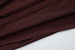 Dettaglio ravvicinato delle cuciture overlock e della trama in maglia dell'abito bordeaux