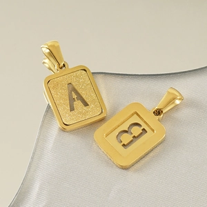 Detail of 18K gold-plated titanium steel letter pendants with sandblasted and polished textures