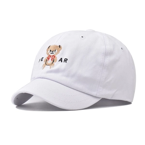 Close-up of white cotton baseball cap showing detailed bear embroidery and texture