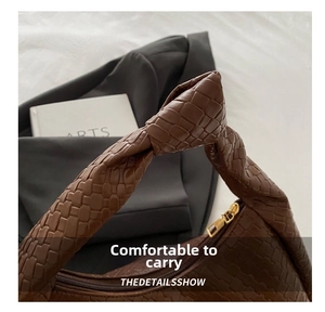 Detailed close-up of dark brown woven handbag featuring a unique knot handle and gold zipper