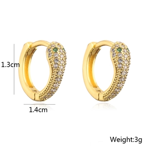 Macro detail of 18K gold snake hoop earrings with zircon paving and green gem eyes