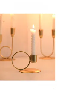 Gros plan détaillé d'un bougeoir en métal doré en U avec une bougie en spirale allumée