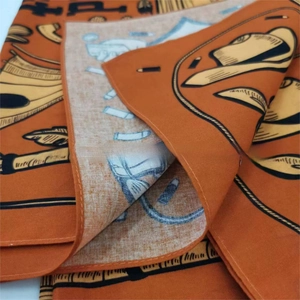 Detail of orange cotton bandana showing feather and ruler prints and fine edge stitching