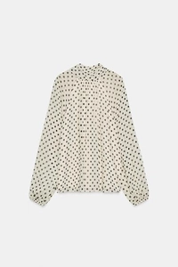 Flat lay of polka dot blouse with long sleeves, elastic cuffs, and elegant stand collar