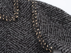 Detailed macro view of grey chunky knit fabric with gold braided sequin trim accents