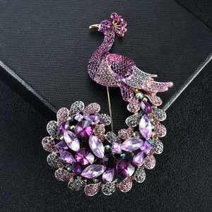 Elegant purple peacock brooch with crystal rhinestones on a black leather texture