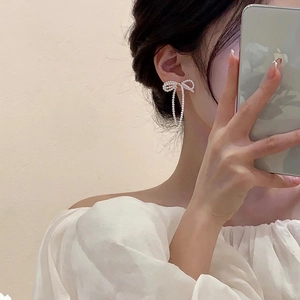 Elegant silver bow earrings with pearl tassels shown on ear in a natural daily style