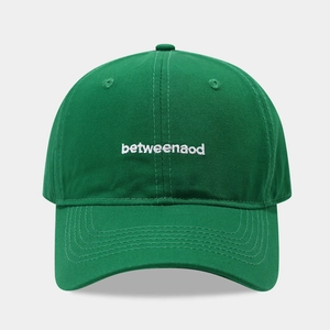 Close-up of deep green baseball cap featuring white letter embroidery and cotton twill texture