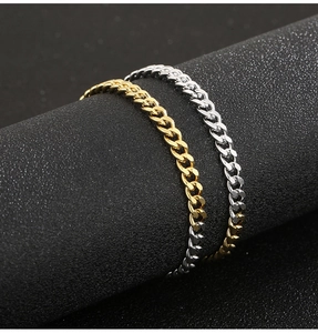 Detail of interlocking gold and silver Cuban link chains on a black textured cylinder