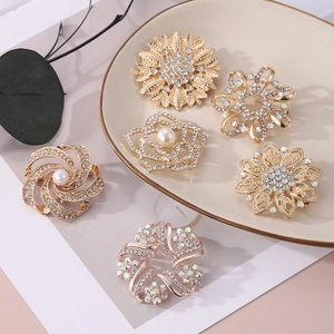 Vue détaillée de broches fleurs dorées avec strass brillants et perles d'imitation
